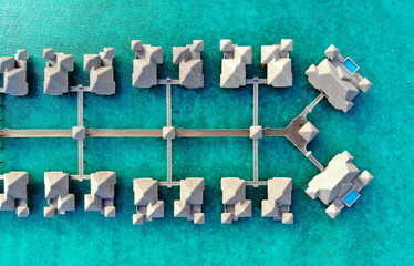 Aerial view of overwater bungalows with thatched roofs in the Bora Bora lagoon in French Polynesia - obrazy, fototapety, plakaty