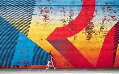 Abwaschbare Fototapete Graffiti Junges Mädchen, das mit Graffiti an der Wand vorbeigeht
