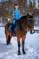 young woman with red hair on a horse in winter