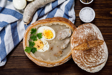 Sour rye soup in bread on wooden table