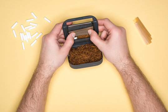 Partial view of man holding snuffbox in hands isolated on yellow