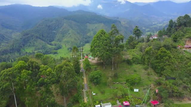AERIAL: climbing past El Mirado to see the valley beyond the precious town of Salento, Colombia on a bright and sunny day.