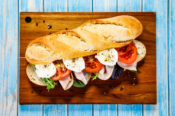 Long sandwich on cutting board on wooden table