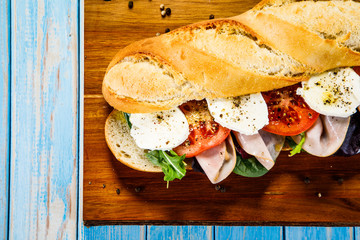 Long sandwich on cutting board on wooden table