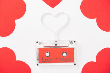 top view of audio cassette with 'love songs' lettering and heart shaped cards isolated on white, st...