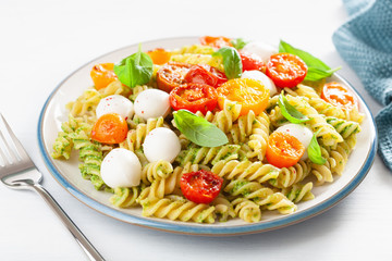 healthy fusilli pasta with pesto sauce, roasted tomatoes, mozzarella