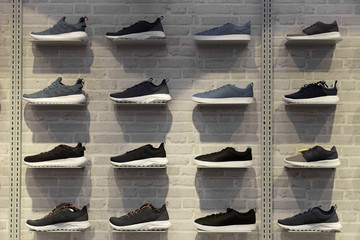 Shop display of unbranded modern new stylish sneakers running shoes for men on brick wall background texture.