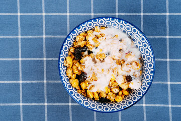 Breakfast preparation. Cereal in a bowl with milk and berries.