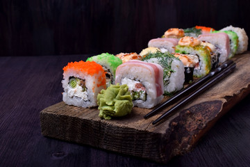 Assortment of baked and fresh sushi rolls on a wooden board. Japanese cuisine