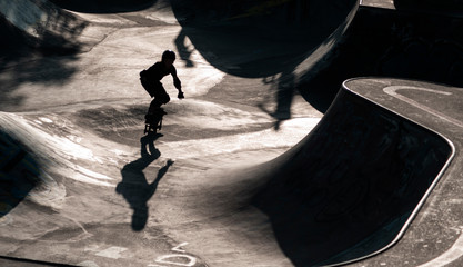 Skater als silhouette im Gegenlicht, im Hintergrund Skatepark