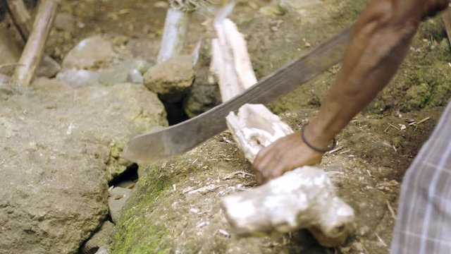 african american caribbean man cutting up log for fire wood on the baech