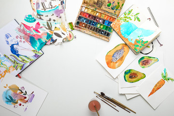 top view of multicolored watercolor paintings and drawing utensils