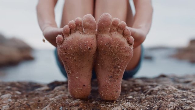 close up of sandy feet young woman sitting on beach barefoot enjoying summer vacation