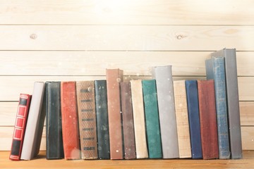 Ancient books in a row on wooden background