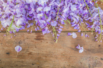 Beautiful frame of blooming purple wisteria on the vintage wooden background with copy space