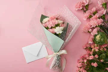 Fotobehang top view of beautiful tender flower bouquet and white envelope isolated on pink © LIGHTFIELD STUDIOS
