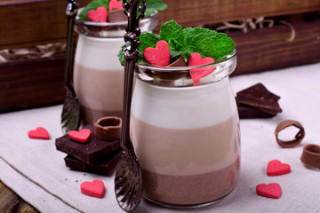 Three chocolate mousse dessert in a glass jar garnished with sugar hearts