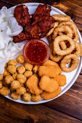 Assortment of fried snacks Onion rings, chicken wings with sauce
