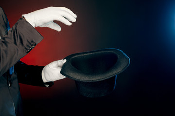 Professional Occupation. Showman in suit and gloves standing isolated on wall making tricks with...