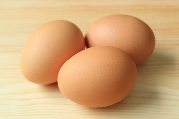Three uncooked fresh chicken eggs isolated on the wooden table 