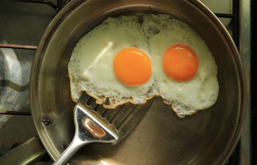 A pair of fried chicken eggs in a fry pan ready for serving 