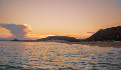 Sea beach and sunset.People at sunset on a deserted beach with mountains