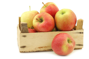 fresh Maribelle apples in a wooden crate on a white background