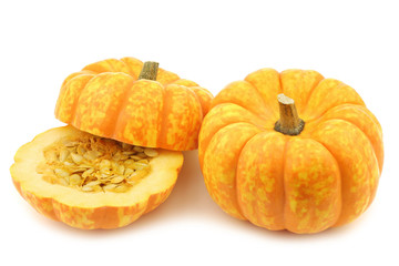 Small yellow and orange pumpkin and a cut one on a white background
