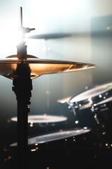 Close-up Drum set in a dark room against the backdrop of the spotlight. Atmospheric background symbol of playing rock or jazz drums. Copper plates on a cold background