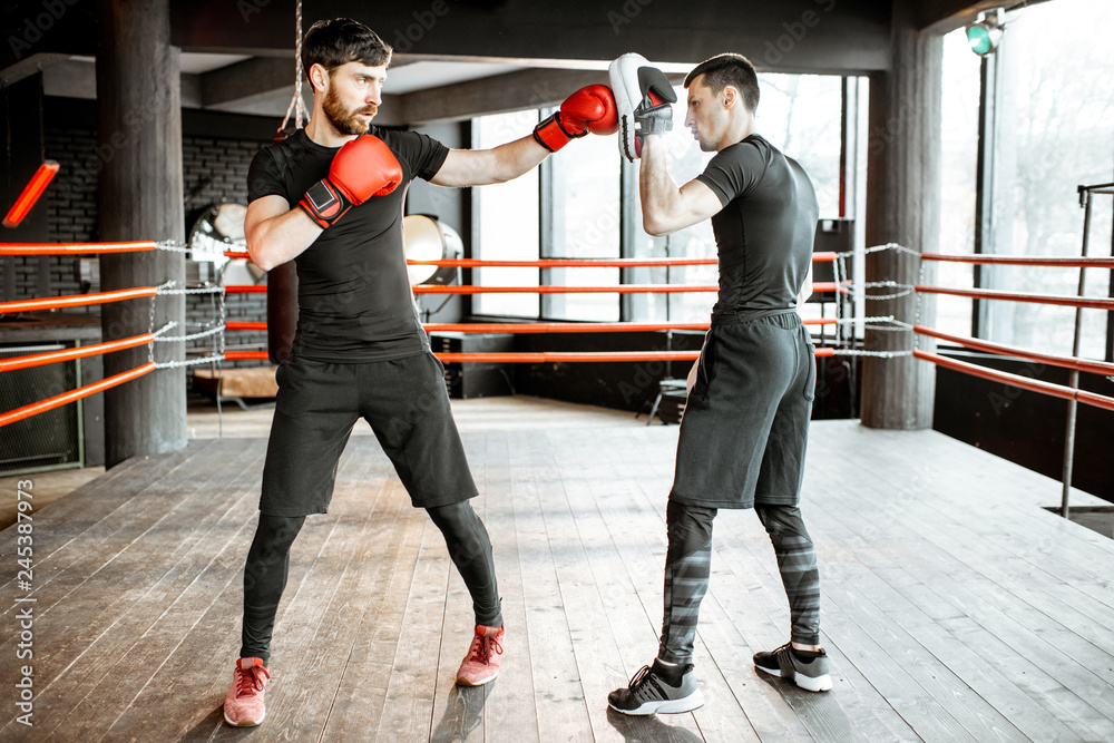 Canvas Prints Boxing trainer showing to a man how to fight, teaching to box on the boxing ring at the gym