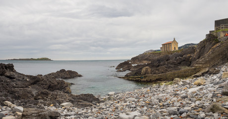 Fototapeta na wymiar Small church of Santa Catalina on the coast of Mundaca village in Biscay during a cloudy day