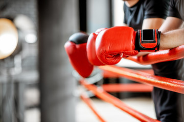 Boxers resting on the boxing ring, close-up view on the boxing gloves on the ropes