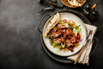 Salad with Roast Beef and vegetables on dark background copy space