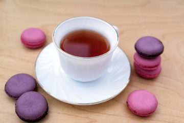 Fototapeta na wymiar Cup of tea with saucer and macaroon on wooden background. Minimalism