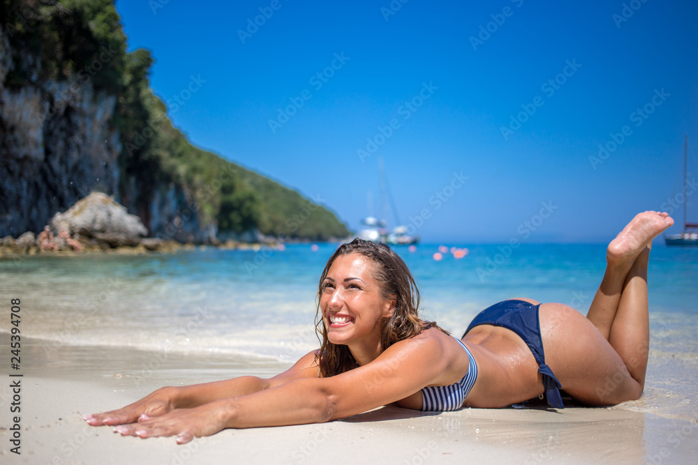 Wall mural beautiful young woman lying on the beach while smiling