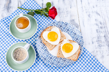 Flowers, Two cups of aromatic coffee and heart-shaped toasts for a romantic morning of lovers. Red rose, letter or note on the table. The concept of Valentine's Day and Mother's Day. Flat lay.  