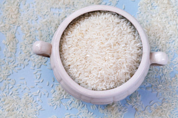 White uncooked rice in mug on blue background. Carbohydrates, healthy food. Place for text.