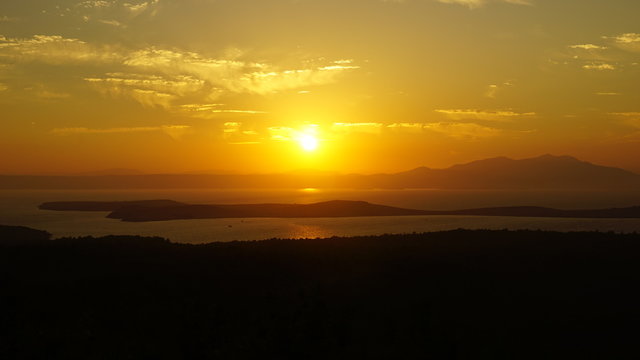 Sunset over sea at Devil's Table (Şeytan Sofrası). Bright dramatic sky and dark blue ground. Beautiful landscape under scenic colorful orange sky at sunset. Sun over skyline. Warm yellow color concept