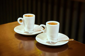 Two cups of espresso coffee on a dark background.