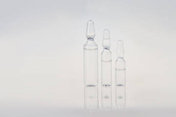 Raw of ampoules with liquid for injection. Break-seal glass ampules with medicine liquid on gray...