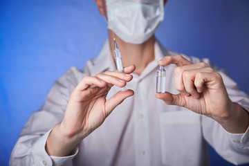 Doctor in mask with a injection syringe  on the blue background