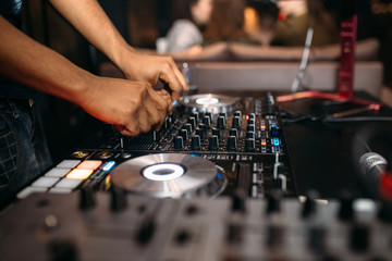 Close up of DJ's hand playing music at turntable on a party festival - Portrait of DJ mixer audio in a beach club above the crowd dancing and having fun - Party, summer, music and people concept