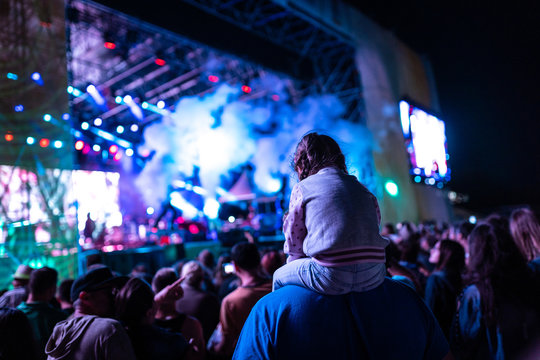 Young girl attending a concert and watching it on her dad shoulders