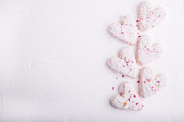 Obraz na płótnie Canvas White heart shaped Valentine's day cookies with white glaze and coconut flakes. Copy space. Flat lay