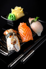 Nigiri Sushi Set of Unagi Eel, Sake Salmon, Tai Sea Bream Perch served on black plate, chopsticks and background.  Traditional Japanese cuisine. Wallpaper