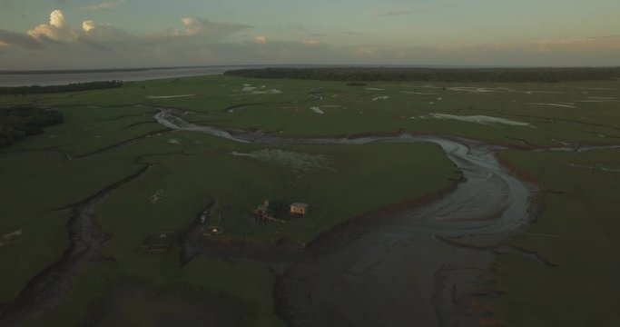 Aerial of Marajo Island Amazon River inlets and tributaries pulling back from a small stilt house in the background at low tide