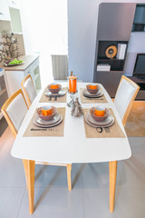 Dining table with contemporary tableware and festive decor in small kitchen