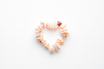 a necklace of pink shells in the shape of a heart.shell frame on white background.with copy space