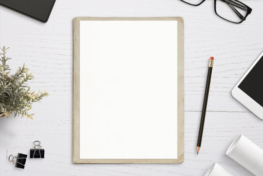 Empty paper mockup, on old folder, white wooden work desk. Top view, flat lay.