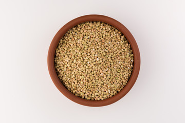 Natural fresh green buckwheat in bowl isolated on white background, top view